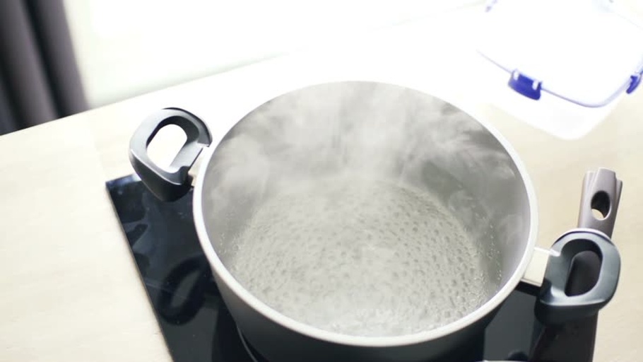 正在用小火慢煮的锅中,姜片和菊花在水中翻滚,蒸汽升腾,背景为厨房环境 姜和菊花煮水的过程图