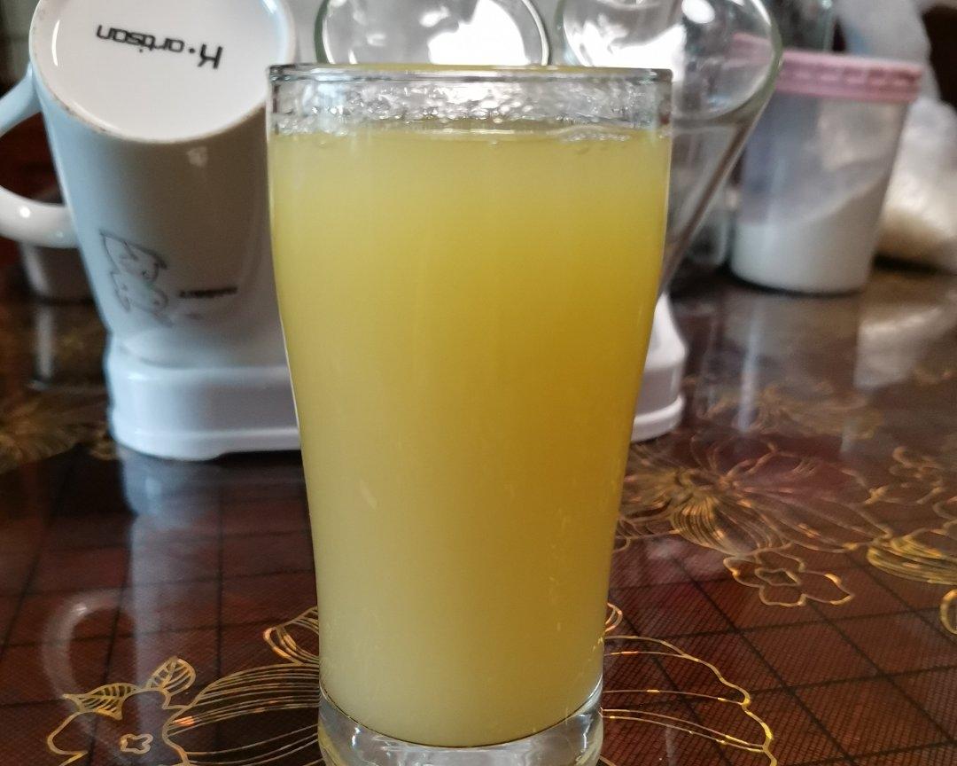 玻璃杯中盛着浅绿色清新果汁，漂浮着薄荷叶和橙色果肉碎