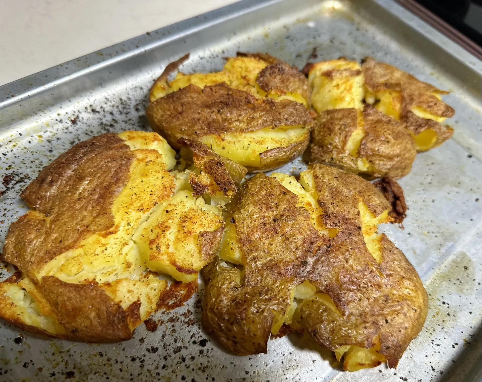 高清俯拍:烤至完美的法式土豆块,块状规整饱满,表皮呈现琥珀色焦糖脆壳,嵌有翠绿香草碎,油脂反光自然,呈现高级餐厅质感 法式烤土豆块俯拍:金棕色立方体土豆块堆叠在黑色石板烤盘中,表面油润酥脆,可见深绿色迷迭香碎与灰绿色百里香叶,边缘微翘起焦边,散发温暖香气感
