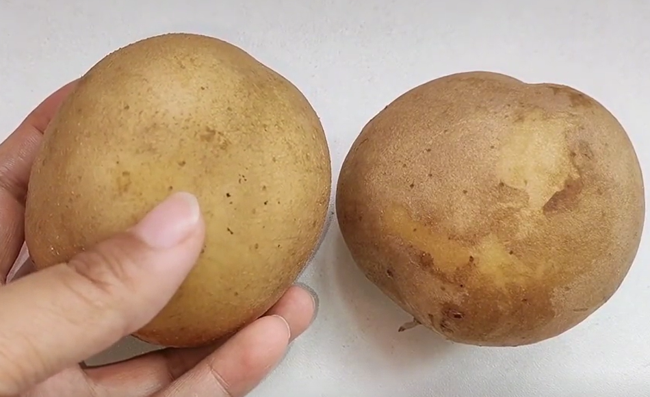 新鲜蒸熟的棕色或黄色皮马铃薯,表面微湿有光泽,部分已切开露出淡黄色内部,旁边放有一把不锈钢叉子,展示健康烹饪方式 蒸煮后的带皮马铃薯特写