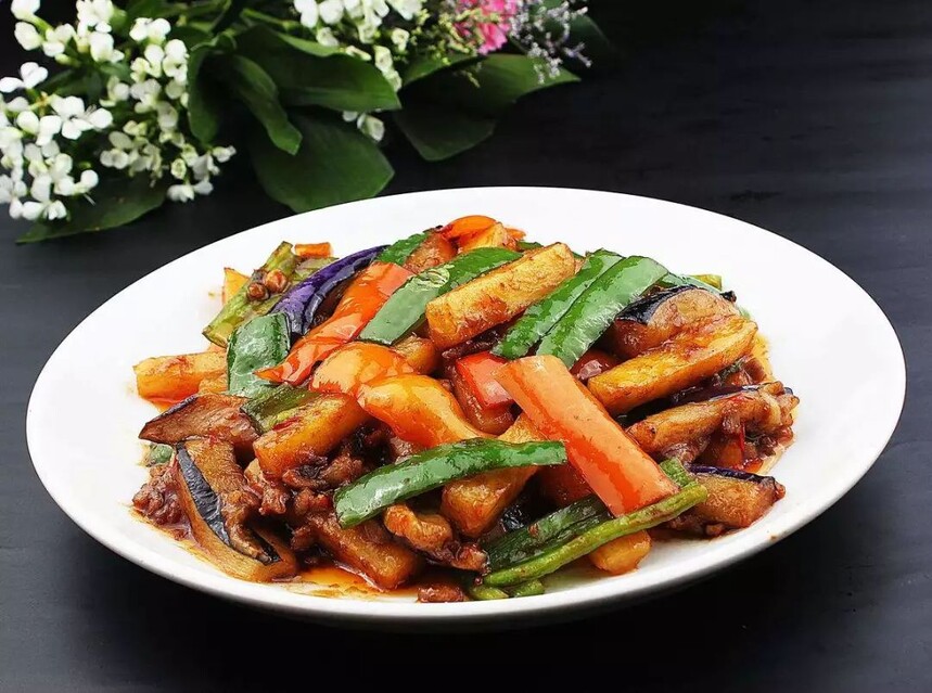 一盘色泽红亮、油润诱人的地三鲜,茄子、土豆、青椒块均匀分布,表面微焦,点缀葱花,背景为木质餐桌,体现家常氛围 地三鲜成品图