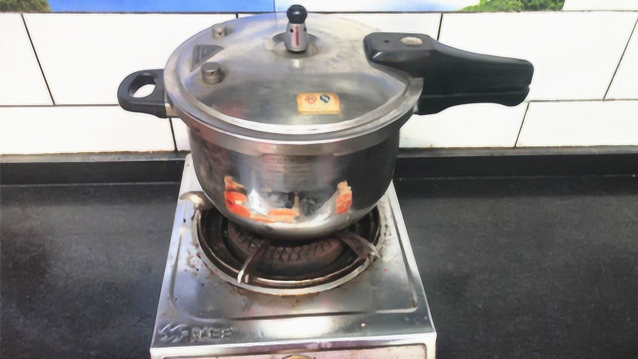 一个不锈钢高压锅放置在炉灶上,锅盖已密封,旁边摆放着清洗干净的整颗土豆和切块土豆,背景有蒸汽升腾的效果,展示高压锅正在工作状态 高压锅蒸土豆示意图