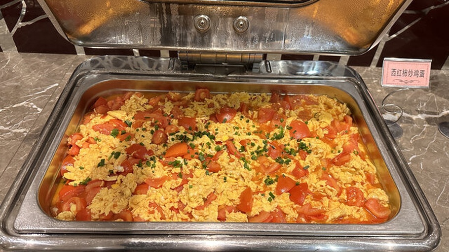 锅中正在翻炒的西红柿炒鸡蛋，香菜已加入