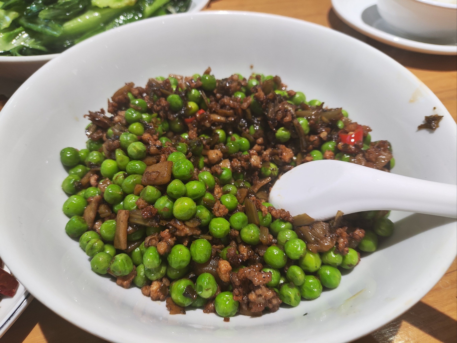 青豌豆炒搭配米饭装盘，旁边配有中式碗碟