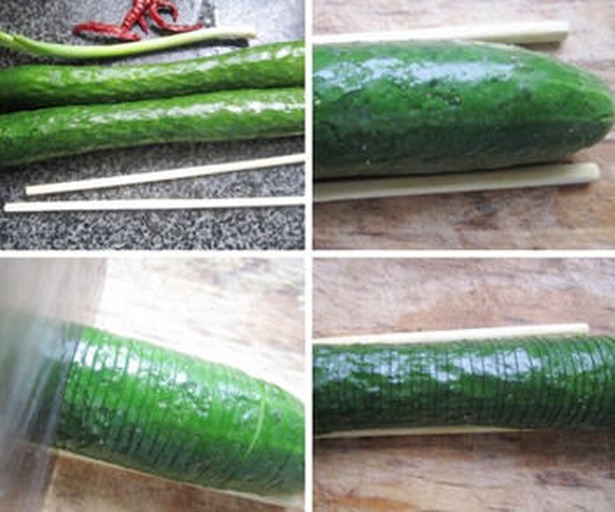 拍裂小黄瓜操作过程图 厨师正在用刀背拍打一根新鲜小黄瓜,黄瓜已裂开但未断开,案板上有裂痕痕迹