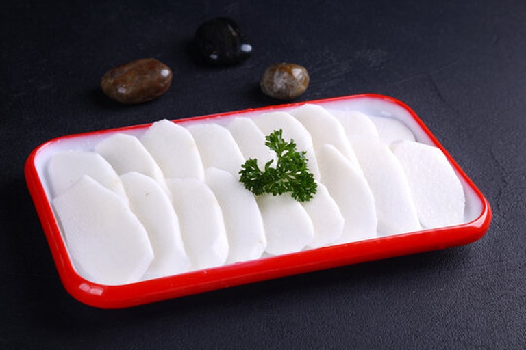 一盘刚出锅的水果萝卜炒肉,粉白相间的萝卜条与棕褐色的肉片交错分布,表面泛着油亮光泽,点缀着翠绿的蒜苗,盛放在白色瓷盘中,背景虚化体现美食摄影质感 水果萝卜炒肉成品图