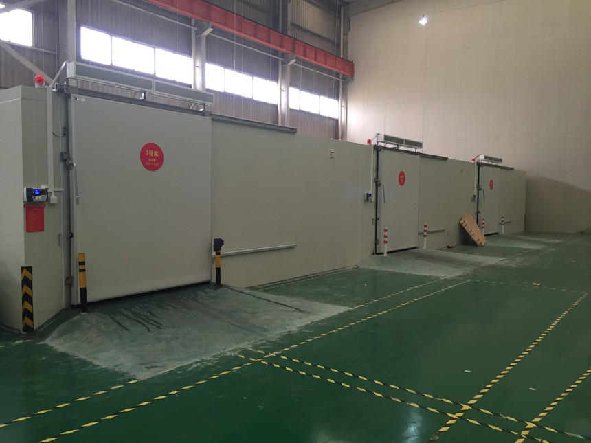 山东莱阳水晶梨产地仓实景：蓝色标准化冷库外立面，叉车转运印有“莱阳水晶梨·全程冷链”字样的蓝色周转筐，筐内果实整齐码放，背景可见温度监控屏显示“4.2℃”