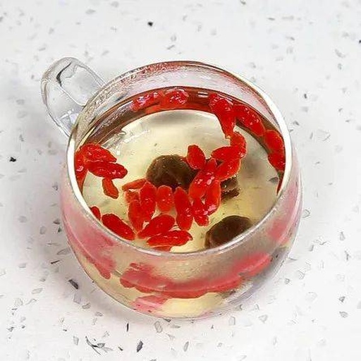 玻璃罐中盛放着刚煮好的红枣枸杞茶，液体呈琥珀色，几片红枣漂浮其中，旁边摆放木质茶匙