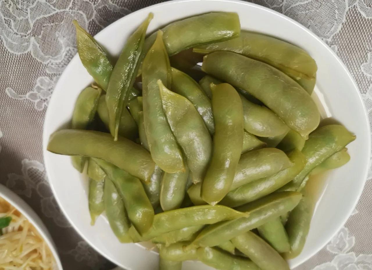 一盘清炒荷兰豆摆放在白色餐盘中,色泽翠绿,看起来非常诱人 清炒荷兰豆成品图