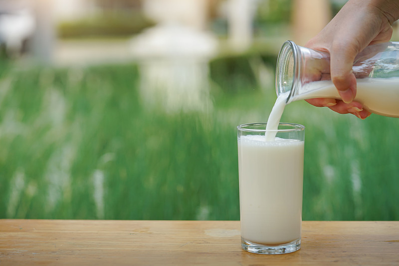 玻璃杯中盛放着由切块牛奶青枣与纯牛奶混合搅拌而成的粉白色果蔬饮,杯口点缀一片青枣薄片,旁边摆放整颗青枣和一瓶冷藏牛奶,展示家庭健康饮品制作场景 牛奶青枣与牛奶搭配饮品