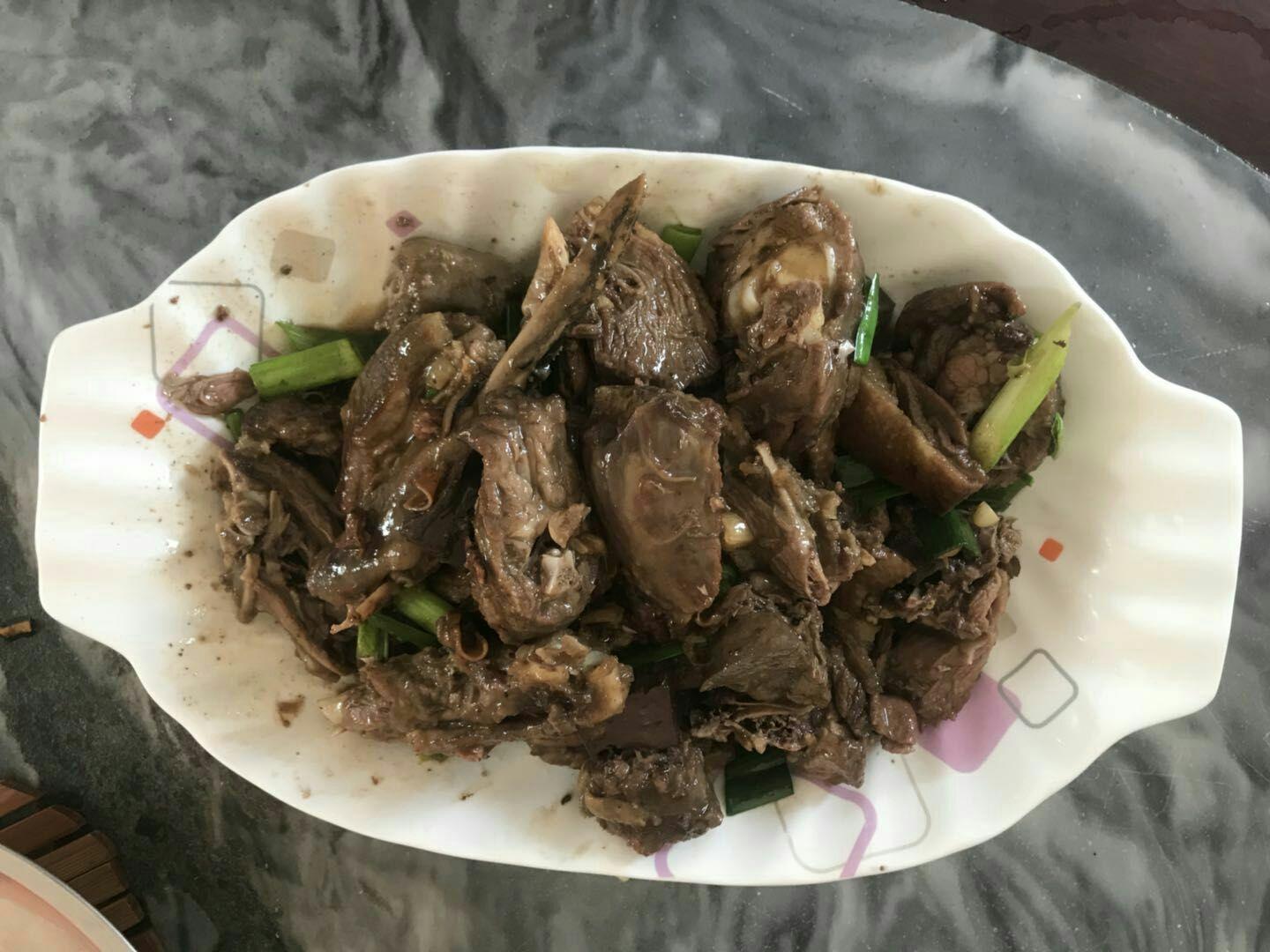 厨师正在铁锅中用猪油煸炒切片的深黄色姜母,姜片边缘微卷,散发出浓厚蒸汽,背景可见整只鸭子待入锅,体现传统闽南姜母鸭制作工艺 姜母鸭制作过程中的姜母煸炒场景