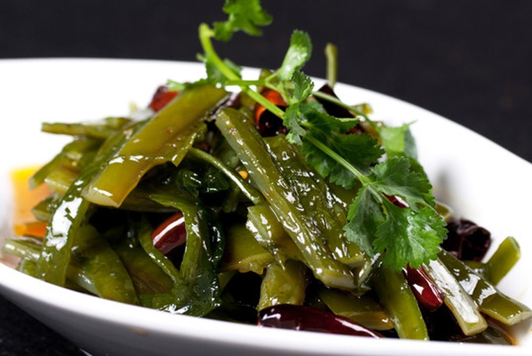 俯拍美食拼盘:左上为蒜香麻酱拌海带丝(墨绿丝状,点缀红油与白芝麻),右上为清炒海带肉丝(棕褐肉丝与翠绿海带交织,油亮诱人),下方为海带豆腐羹(奶白羹体中浮着墨绿海带丁与嫩黄豆腐丁,撒翠绿葱花) 三款海带丝成品摆盘图
