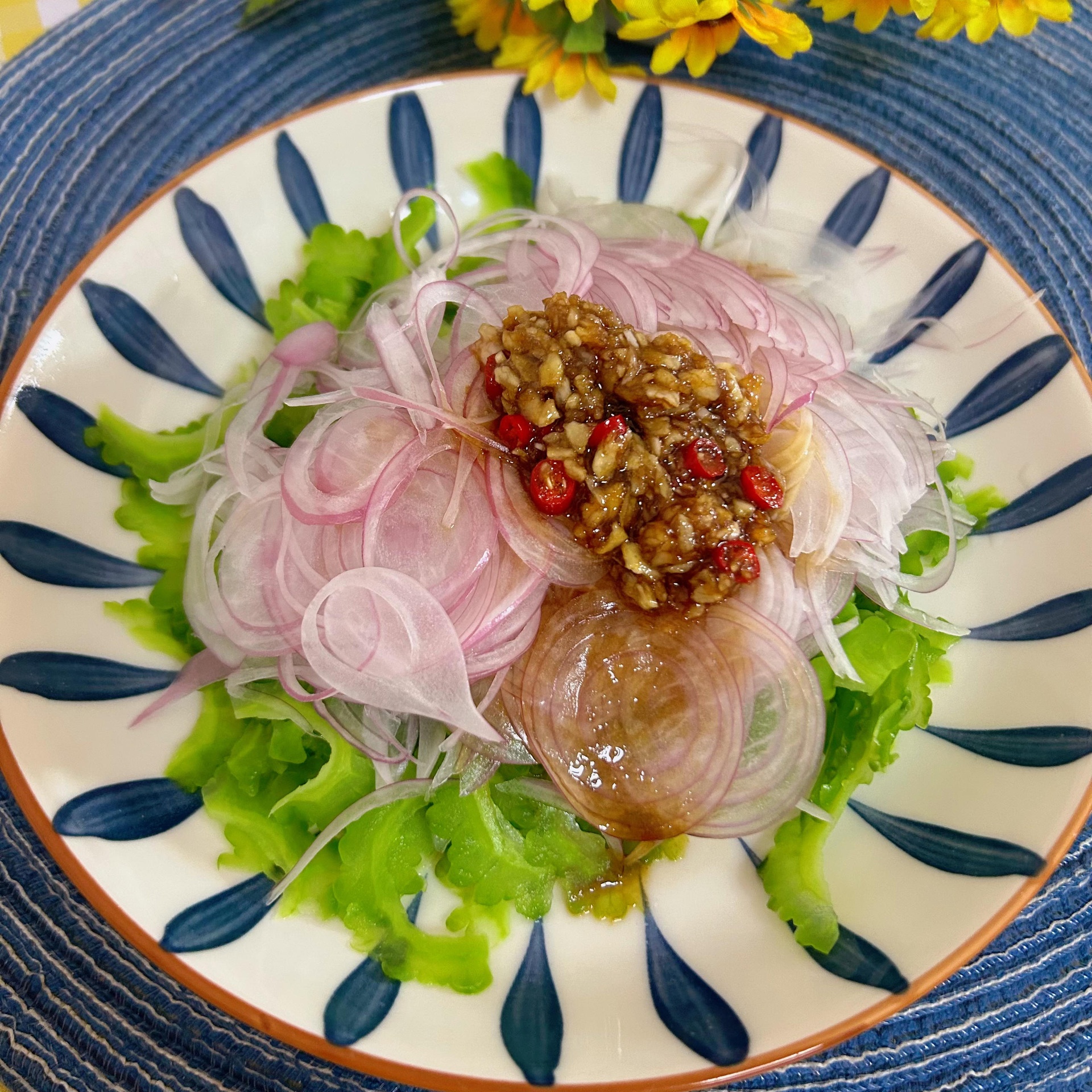 青皮苦瓜凉拌菜成品：翠绿苦瓜片铺底，点缀红椒丝与蒜末，淋薄层橄榄油，盛于青瓷浅盘，体现低脂烹饪方式