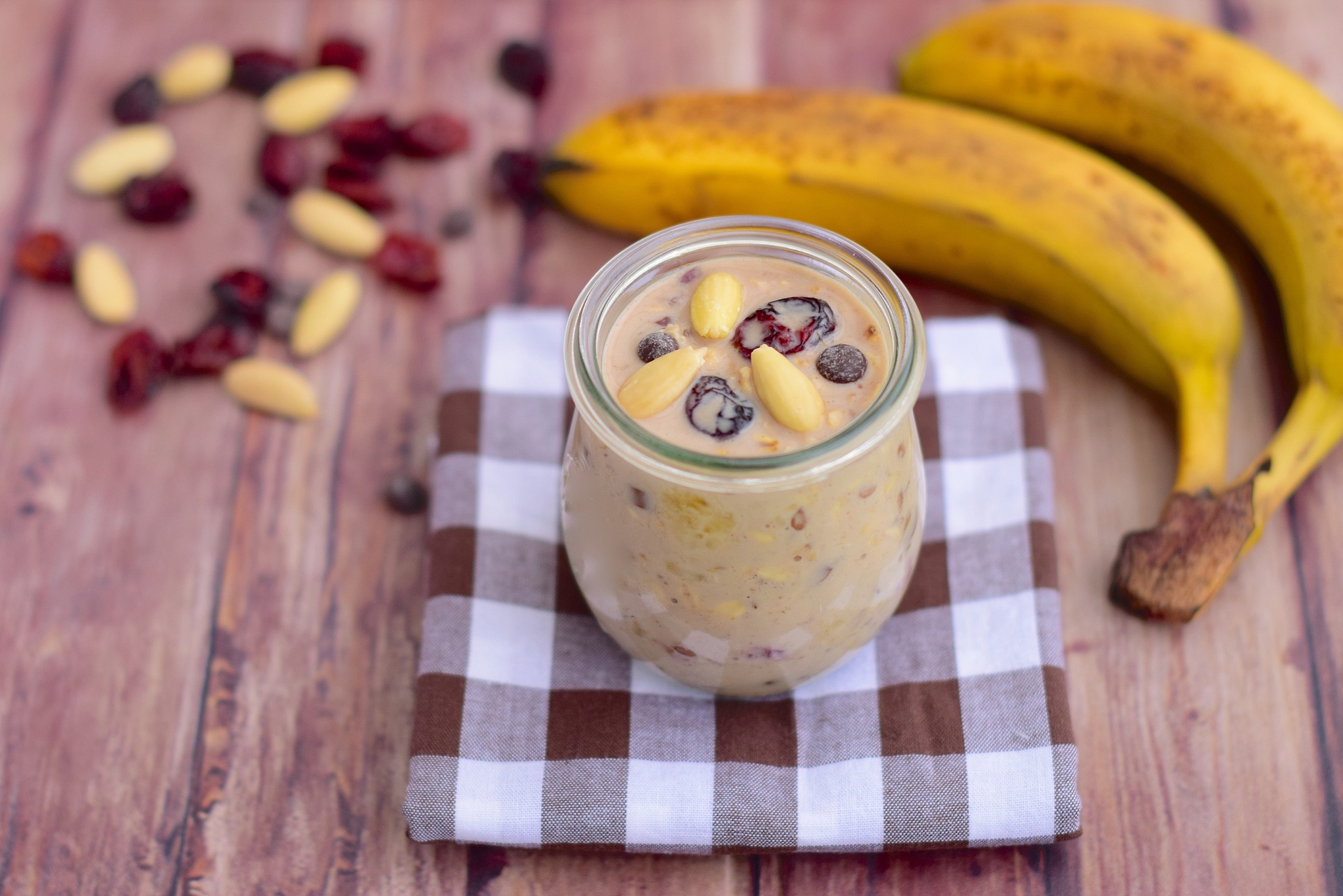 莲藕香蕉燕麦椰奶饮品呈奶油色,装在透明玻璃杯中,旁边摆放香蕉片和燕麦,营造健康早餐氛围 莲藕香蕉燕麦椰奶饮品
