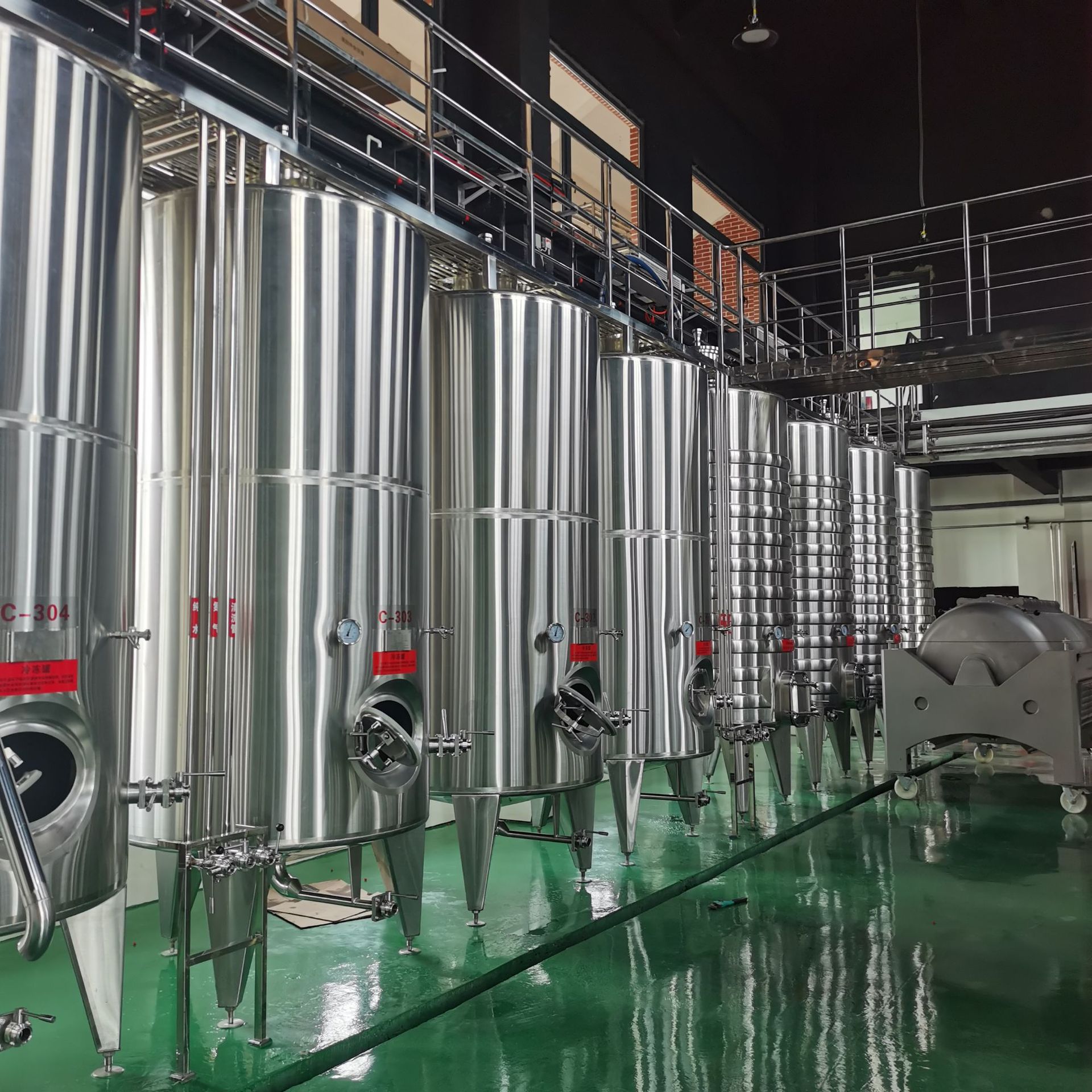 一座现代化的葡萄酒酿造车间内部场景,不锈钢发酵罐整齐排列,工人正在监控温度控制系统,输送管道连接压榨机与澄清设备,地面洁净无尘,墙上标有‘Malbec Fermentation’字样,体现专业化生产流程 现代化葡萄酒酿造车间