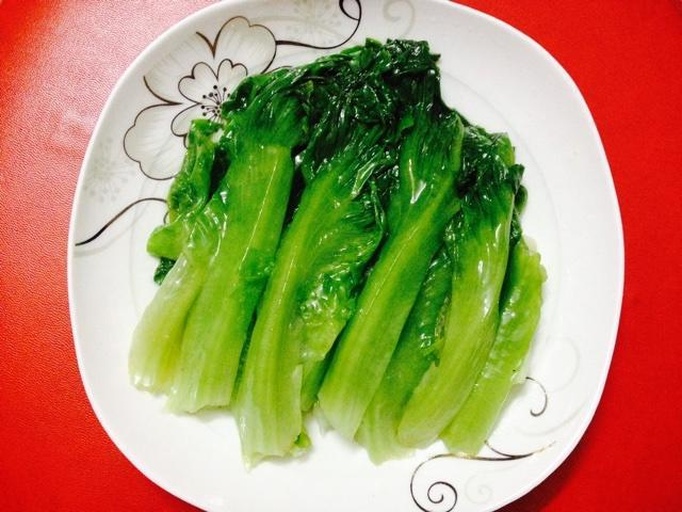 一张中式家庭餐桌上摆放着一盘清炒油麦菜,色泽碧绿,香气扑鼻,旁边配有白米饭和陶瓷碗筷,营造出健康饮食的生活场景 家庭餐桌上的油麦菜菜肴