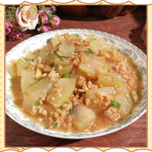 白皮冬瓜与猪肉末摆放在木质案板上，旁边有姜蒜葱等辅料，背景为厨房操作台