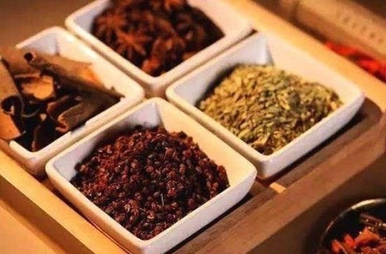 一组常见的中式炖肉香料,包括八角、桂皮、香叶、白芷、草果、小茴香等,其中白芷为浅色圆柱形切片,与其他深色香料形成对比,整齐摆放在木质托盘上 中式炖肉香料组合