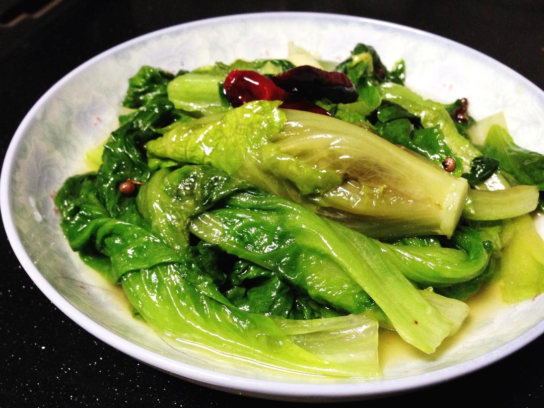 铁锅爆炒生菜过程特写：锅中青翠生菜在烈火中翻飞，蒜末金黄分明，油星细密跃动，无焦黑、无出水，呈现“锅气裹翠”视觉效果