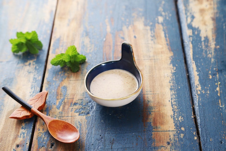 一个木质托盘上摆放着两个被切成四瓣的洋葱，旁边配有柠檬片和绿叶植物，营造自然清新的居家氛围