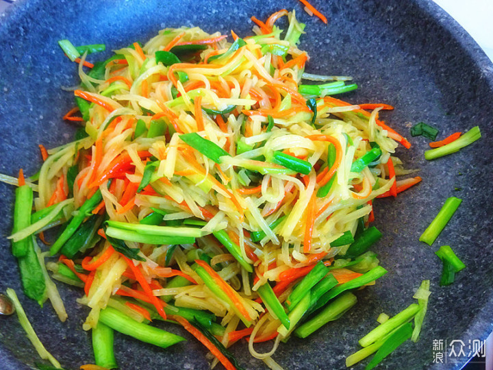 锅中正在翻炒香芹与黄瓜，食材呈翠绿色，蒸汽升腾，厨师手持锅铲翻动