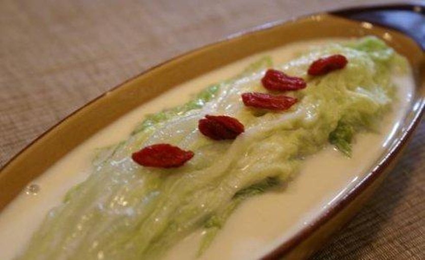 一家中式餐厅的圆桌上摆放着一盘上汤娃娃菜,位于转盘中央位置,周围还有红烧肉、清蒸鱼等其他菜肴,几位顾客正在用餐,灯光柔和,氛围温馨,娃娃菜盛放在白色瓷盘中,汤色清亮,菜叶舒展 餐厅餐桌上的上汤娃娃菜