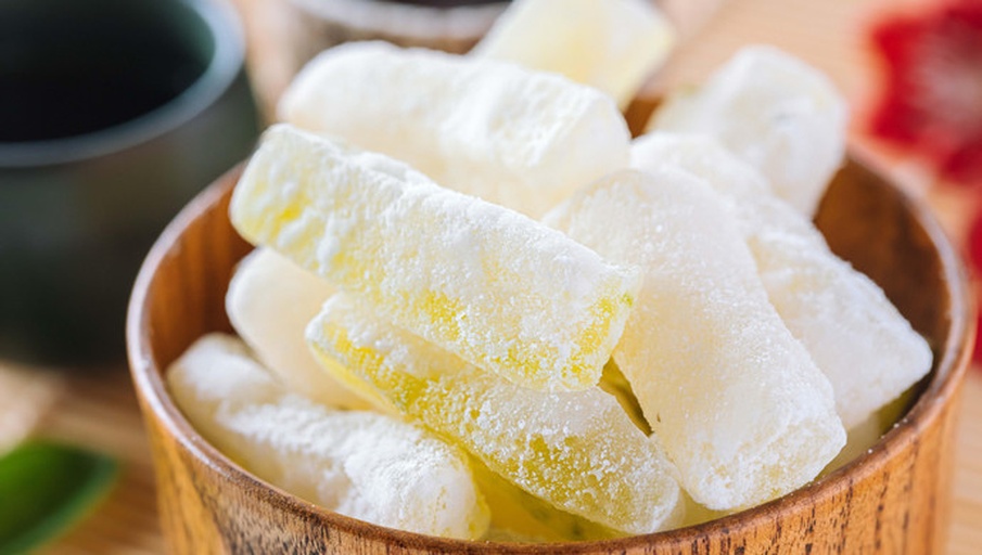 温馨的家庭客厅场景,木桌上放着一盘剥好的沙糖桔,果肉晶莹剔透,几位家庭成员正在开心地分享食用,孩子手中拿着一瓣果肉放入口中,脸上露出满足的笑容,背景有节日装饰,营造出温暖氛围 家庭场景中一家人围坐剥食沙糖桔