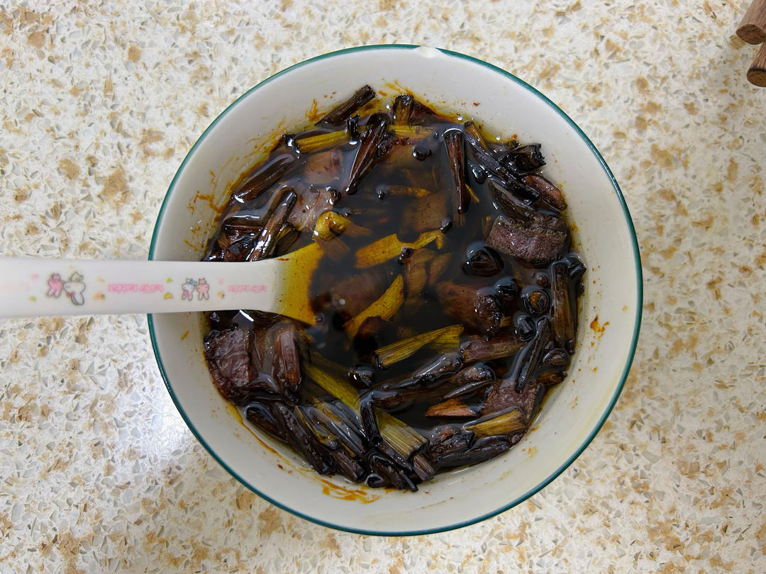 一碗热气腾腾的深棕色炖菜,里面有深色腊肉片和黄褐色的莴苣干,汤汁浓郁,旁边配有木筷和瓷碗,背景为 rustic 风格餐桌 莴苣干菜与腊肉炖煮成品图
