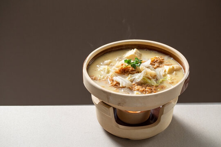 黄心白菜炖豆腐高清成品图:突出砂锅器皿、豆腐金黄完整、白菜三段质地对比、汤汁清亮挂勺、香油光泽明显,体现‘暖胃醇厚’质感 黄心白菜炖豆腐成品特写:砂锅中盛放琥珀色清亮汤汁,漂浮着金黄煎豆腐块与层次分明的白菜块(外帮软润、中段微韧、内芯嫩黄),表面淋有晶莹香油,撒少许白胡椒粉