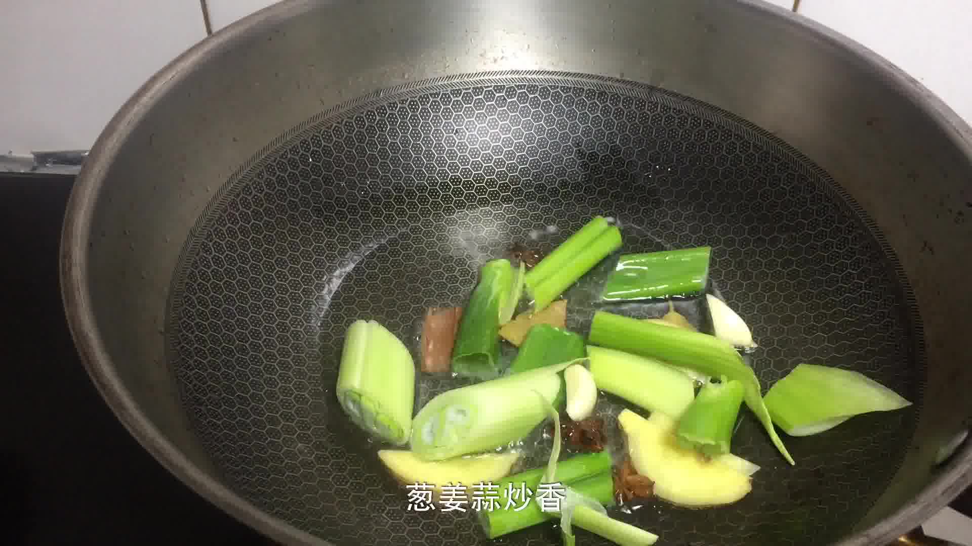 一口黑色铁锅正置于燃气灶上,锅中翻炒着翠绿的无筋豆,大蒜片清晰可见,蒸汽升腾,厨师手持锅铲正在进行颠勺动作 无筋豆在炒锅中翻炒的过程