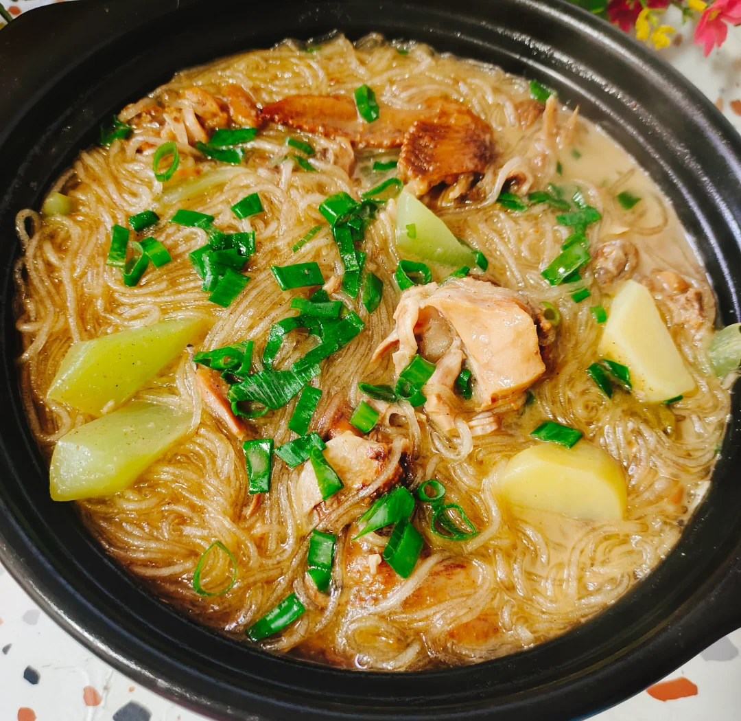 砂锅中正在炖煮的白菜豆腐五花肉炖粉条,汤汁微沸,可见金黄五花肉片、白色豆腐块、淡黄色白菜帮与透明红薯粉条交织在一起,表面浮着点点红亮油星和葱姜香料,热气升腾,展现浓郁诱人的炖菜状态 炖煮过程特写