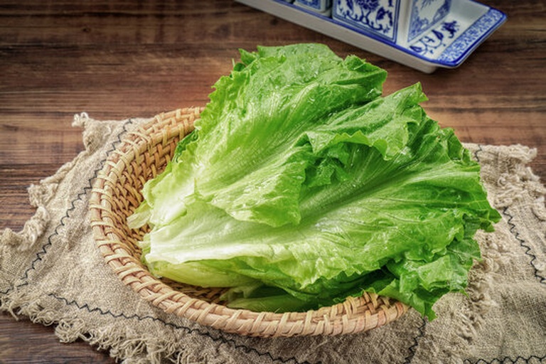 一篮新鲜采摘的绿色生菜叶,叶片呈舒展状,表面有自然光泽,背景为田园农场环境,阳光柔和,突出食材的新鲜与天然来源 图片描述