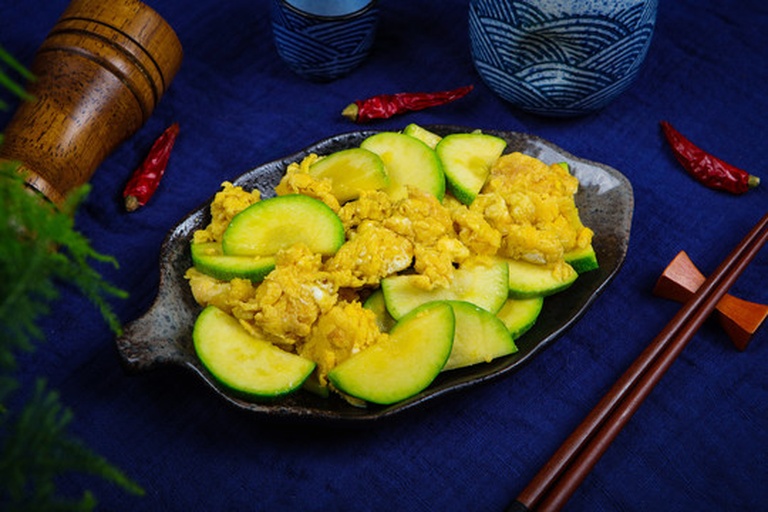 左右分屏对比图:左图为刚出锅的西葫芦炒鸡蛋,色泽明艳、蛋块蓬松;右图为冷藏12小时后经沸水蒸透的成品,西葫芦仍保持翠绿、蛋块略收干但无焦边,盘底洁净无渗水,蒸汽氤氲中可见完整食材形态 西葫芦炒鸡蛋冷藏与复热对比图