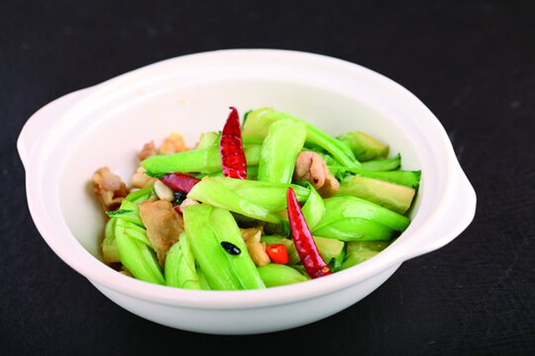 白色瓷碗中盛满金黄色的焖面,面条油润发亮,夹杂着翠绿的白不老豆角和红褐色五花肉片,顶部撒有新鲜葱花,一双木筷正挑起一根根弹牙的面条,背景虚化呈现家庭餐桌环境 一碗盛好的白不老焖面特写,筷子挑起劲道面条