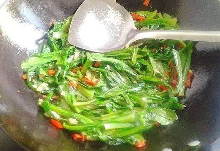 家庭厨房中正在翻炒红菜苔的场景