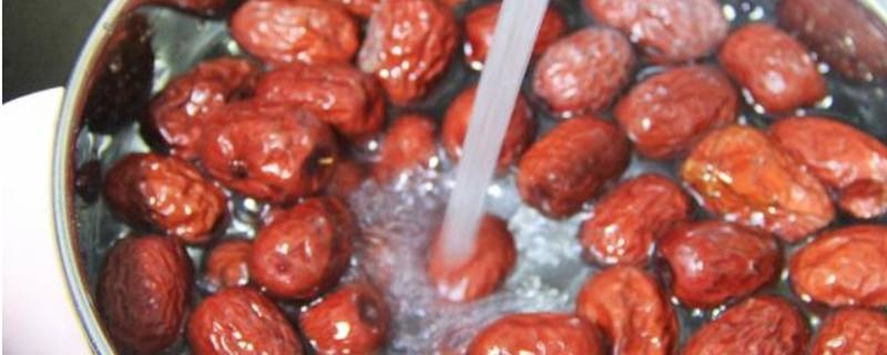 展示青枣在清水中清洗的步骤,操作者正在用清水冲洗青枣,背景为厨房环境 青枣清洗过程