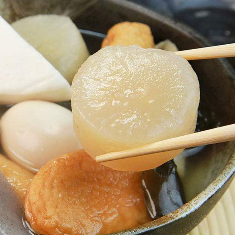 关东煮白萝卜成品图,展示半透明软糯质感,汤汁清亮,摆盘精致,体现日式美学风格 成品关东煮萝卜盛于白色瓷碗中,配以竹筷和柠檬片装饰,背景虚化突出主体