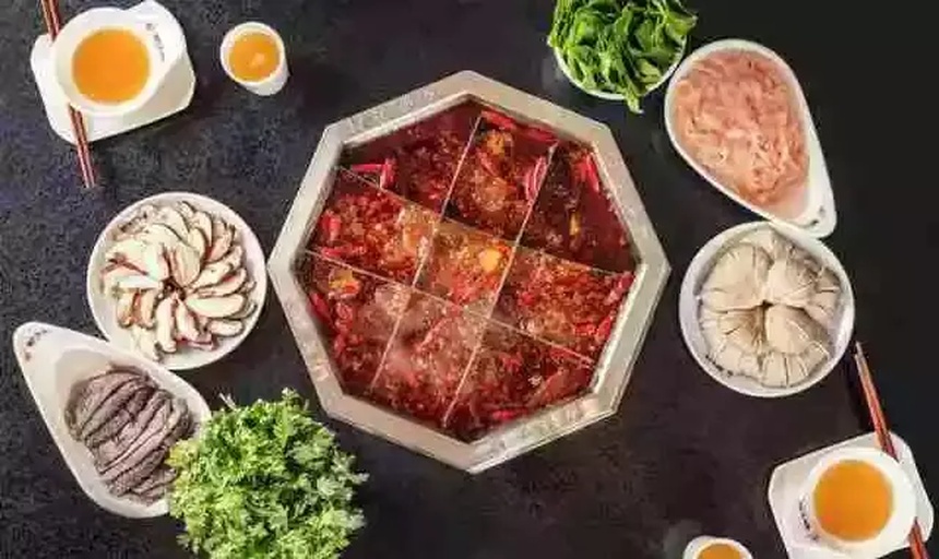 一群朋友围坐在餐桌旁享用麻辣火锅,锅中翻滚着大量红油和辣椒,桌上摆放着新鲜的青红辣椒、香菜等配料。人物表情丰富,有的被辣得满脸通红,有的大笑举杯,展现辛辣美食带来的社交乐趣 人们围坐吃火锅的场景