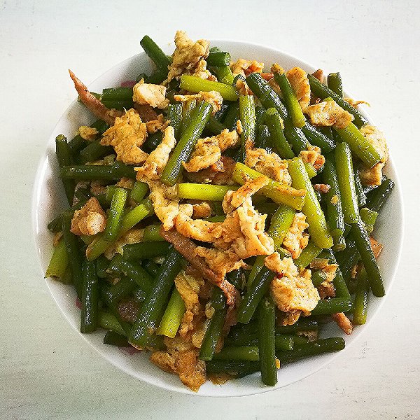 一口铁锅中正在翻炒蒜苔与鸡蛋,食材呈现金黄色与翠绿色交织的状态,火焰轻微上扬,体现‘锅气’十足的烹饪场景 图片描述