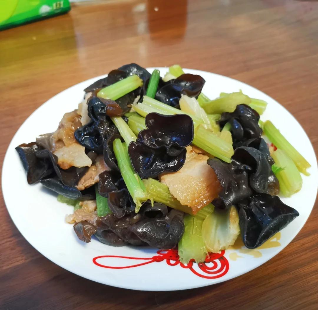 一盘刚出锅的黑木耳炒芹菜盛在白色瓷盘中