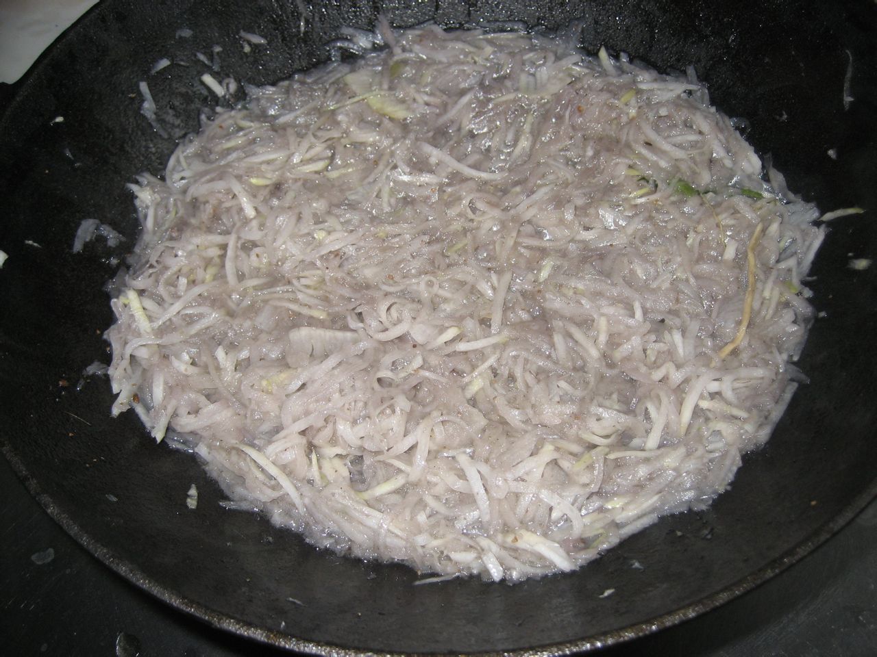 炒锅中正在翻炒茭白与洋葱混合食材,颜色呈现金黄与乳白相间,锅中有轻微油烟上升,体现大火快炒的状态 图片描述