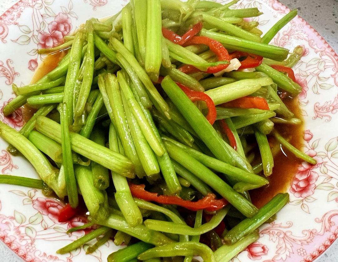 厨房台面上摆放着一把刚洗净的红菜苔,旁边有切好的蒜片和炒锅,锅中红菜苔正在翻炒,热气腾腾,油光闪亮,呈现出一道家常美味的制作瞬间 红菜苔烹饪过程