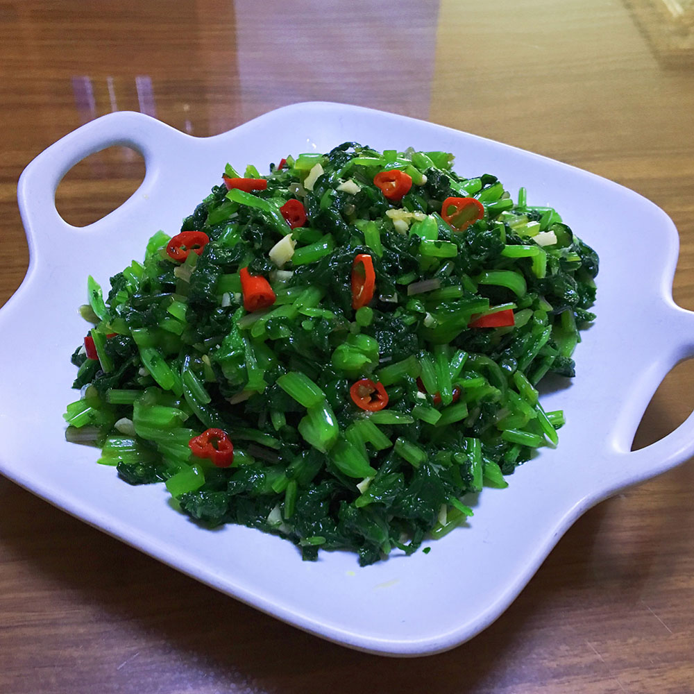 一盘刚出锅的清炒甘蓝摆放在木质餐桌上,菜肴色泽翠绿油亮,蒜香四溢,旁边配有米饭和筷子,整体呈现温馨的家庭用餐氛围 刚出锅的清炒甘蓝成品特写