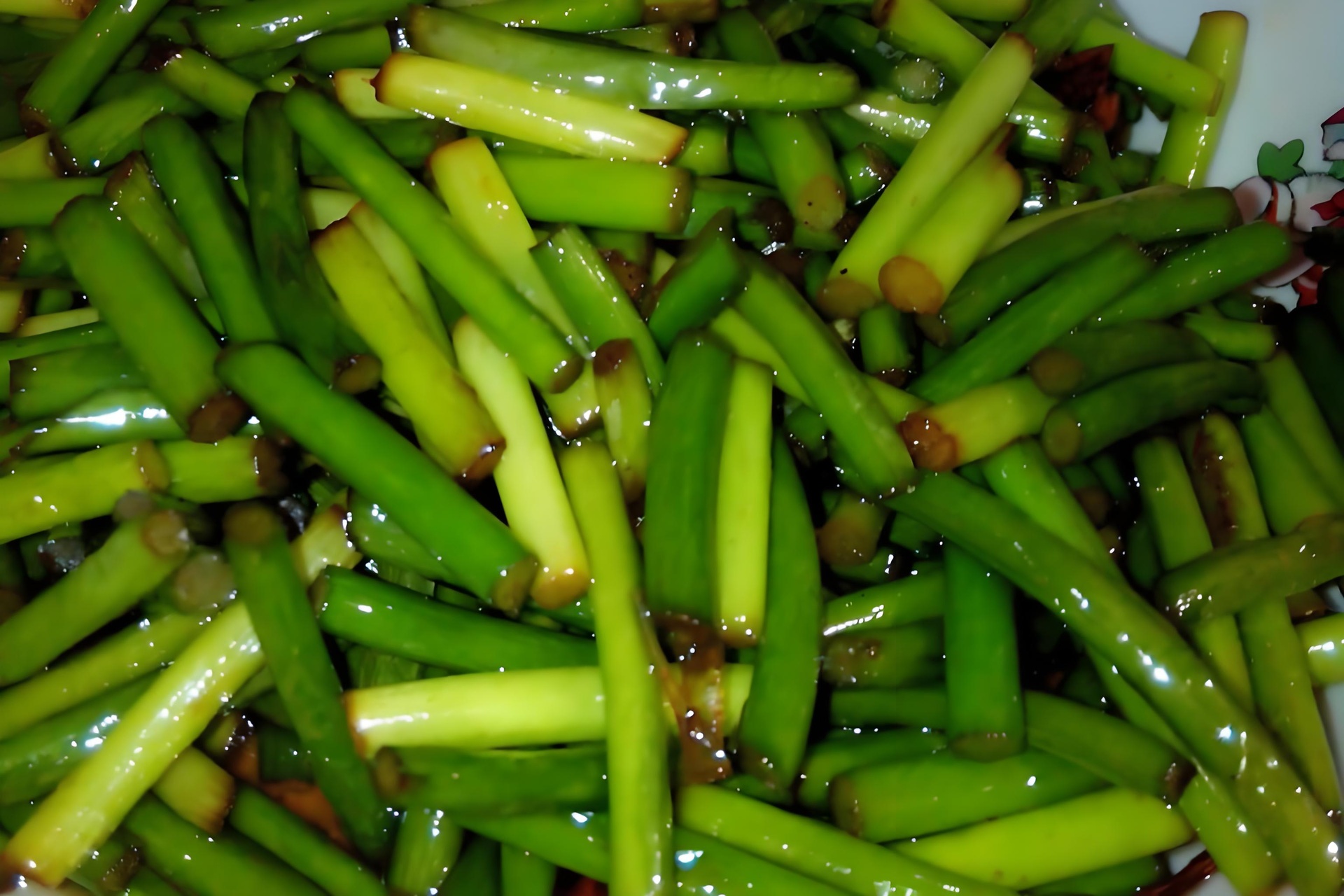 蒜薹家常烹饪对比图：左侧为清水焯烫30秒的翠绿蒜薹（保持脆嫩），右侧为高温快炒2分钟的微黄蒜薹（边缘略卷曲）