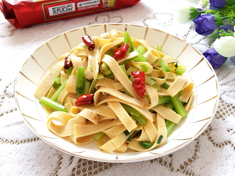 成品香芹炒豆皮高清特写,菜品摆放在白色圆盘中,香芹与豆皮交错分布,表面泛着自然油光,撒有少量白芝麻,整体色彩鲜明,食欲感强 一盘刚出锅的香芹炒豆皮特写,菜肴色泽清亮,香芹翠绿,豆皮金黄,点缀白芝麻