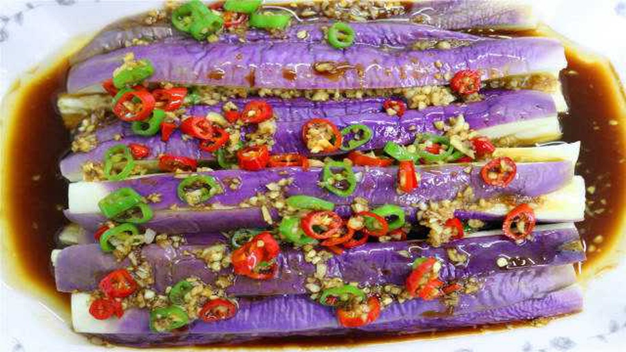 白色瓷碗中盛放凉拌蒜泥茄子,茄子已蒸熟撕成条状,表面均匀裹附乳白色蒜泥酱汁,边缘可见蒜末颗粒,顶部撒有绿色葱花与红色细椒丝装饰,整体色泽清新诱人 一碗刚拌好的蒜泥茄子成品,呈条状摆盘,淋有蒜汁和少许香油,点缀葱花和红椒丝