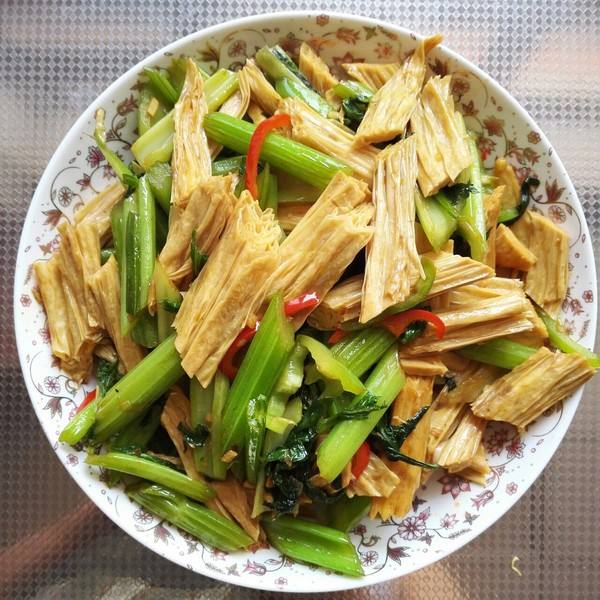 锅中正在翻炒的山芹与香干，食材色泽鲜亮，油光适度