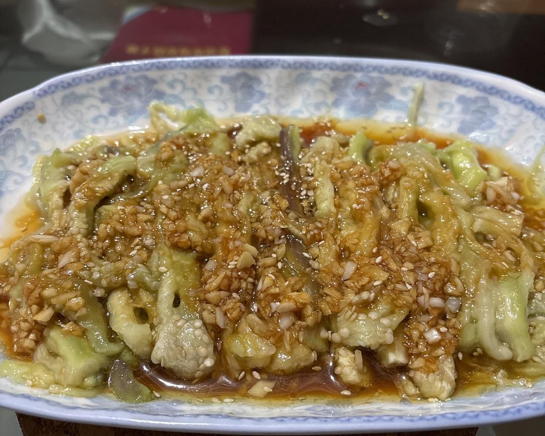 烤青茄子剖开后淋上调料的特写画面