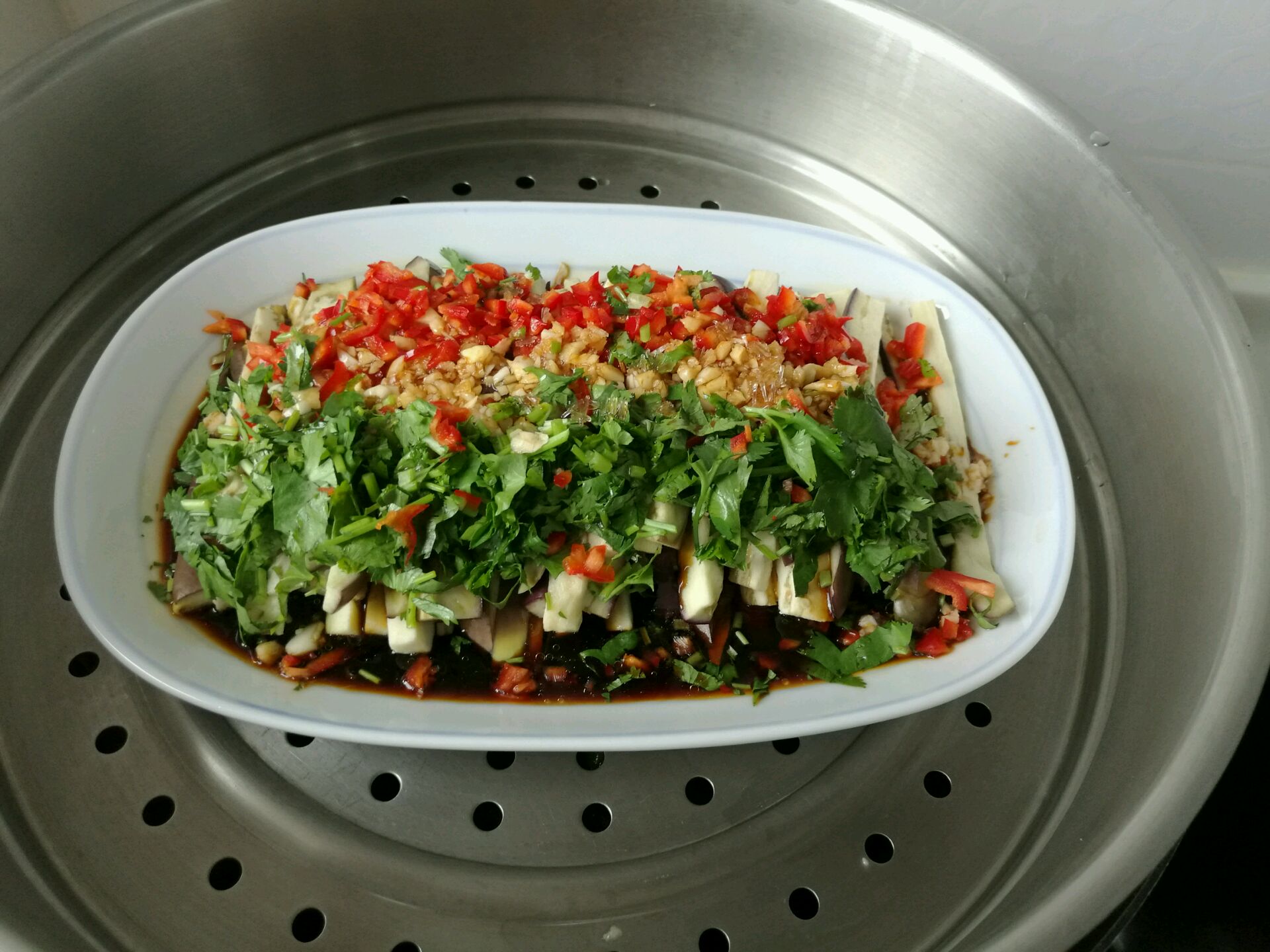 厨师正在铁锅中翻炒酱爆茄子，酱汁浓郁，茄子表面泛着油亮光泽