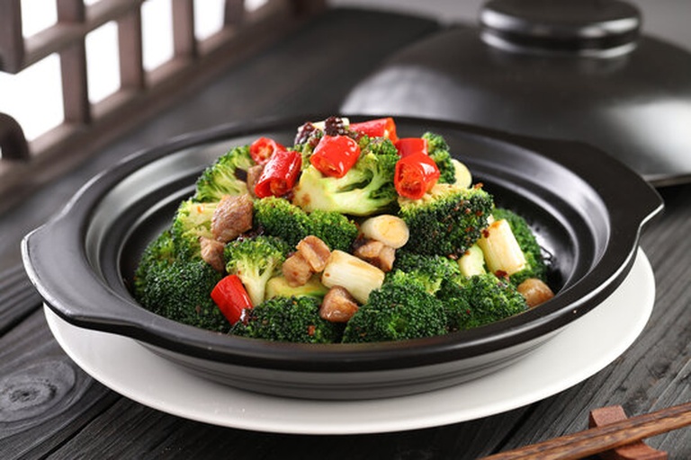 家庭厨房中正在翻炒西兰花与秀珍菇的过程场景